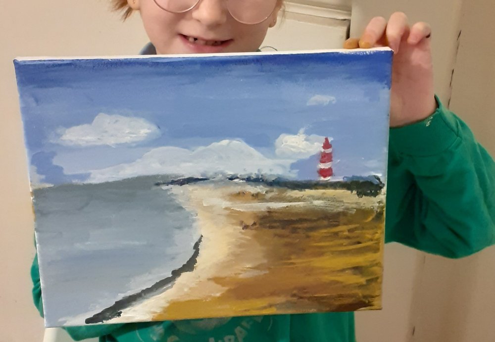 A child proudly holding up a lighthouse beach painting