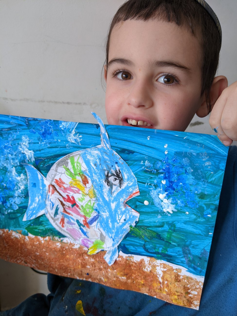 A proud student holding up their fish painting