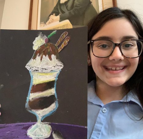 A student smiling next to her oil-pastel ice-cream sundae
