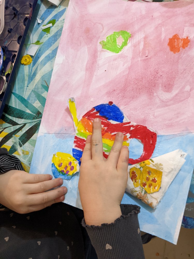 A child colouring a bright rainbow teapot