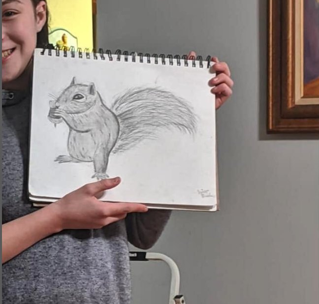 A teen holding a detailed pencil drawing of a squirrel
