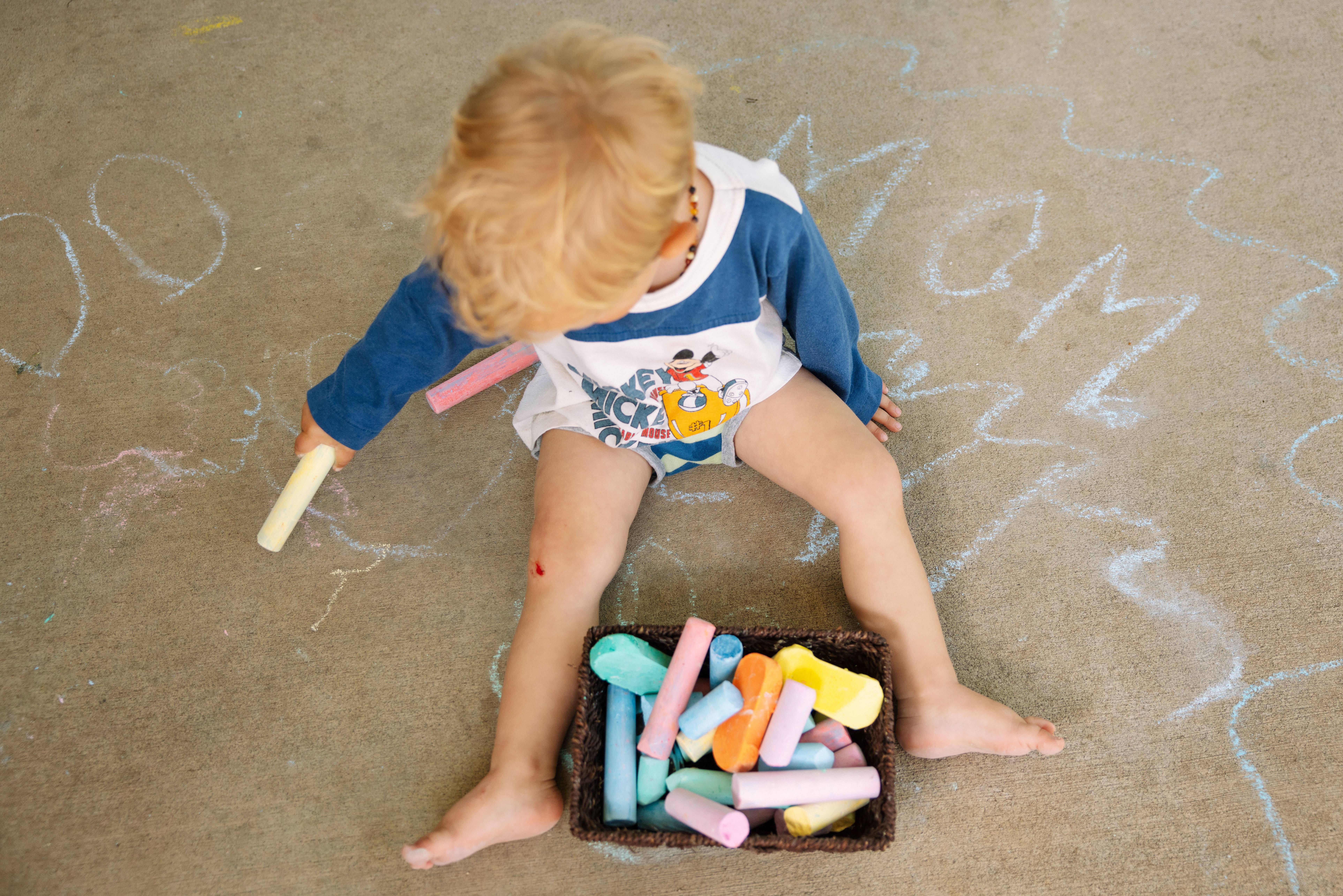 Child playing with colorful sidewalk chalk