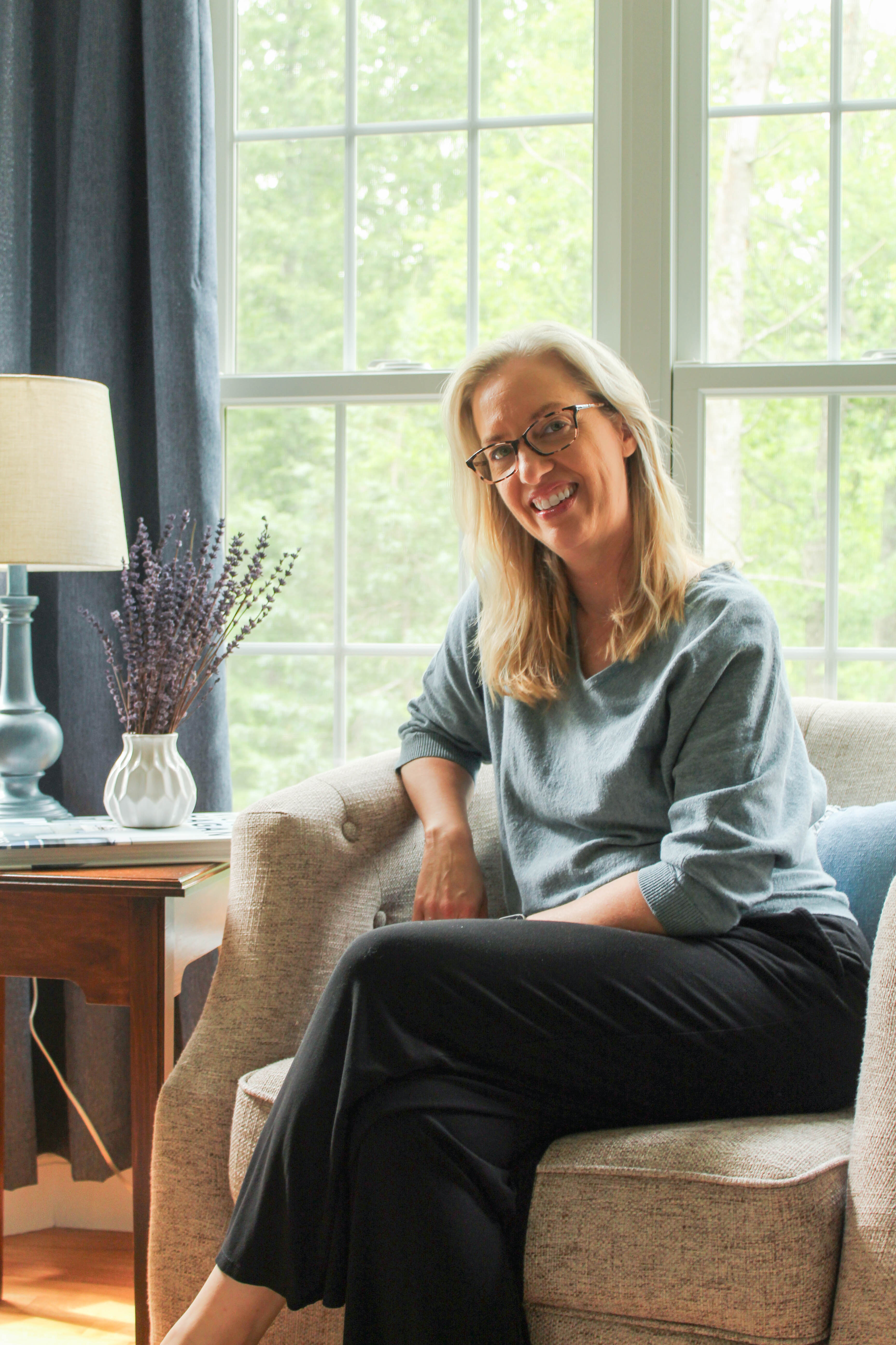 Kristen K. Wold seated in her sunroom with lavender on the side table
