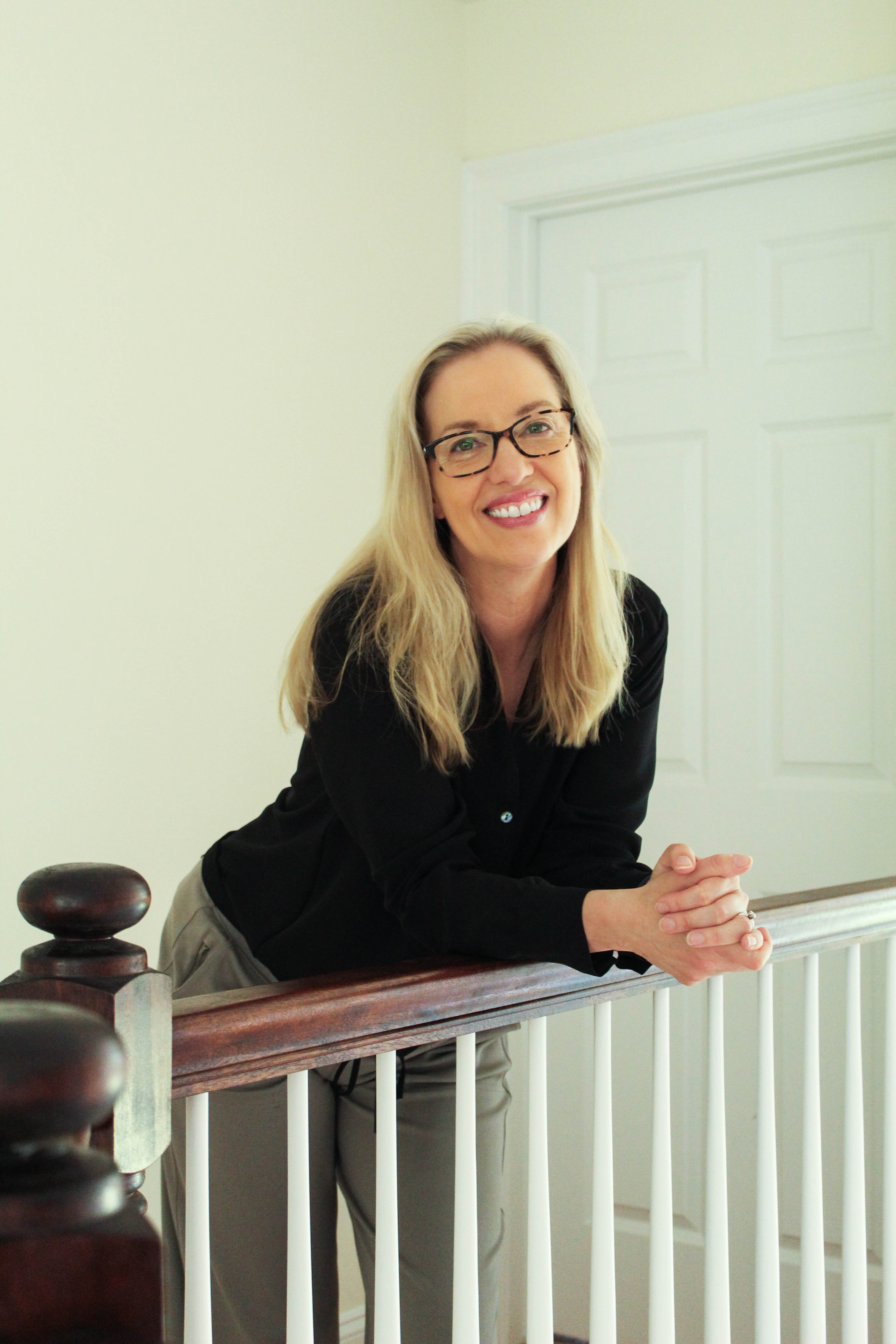 Kristen K. Wold smiling, leaning on a stair railing