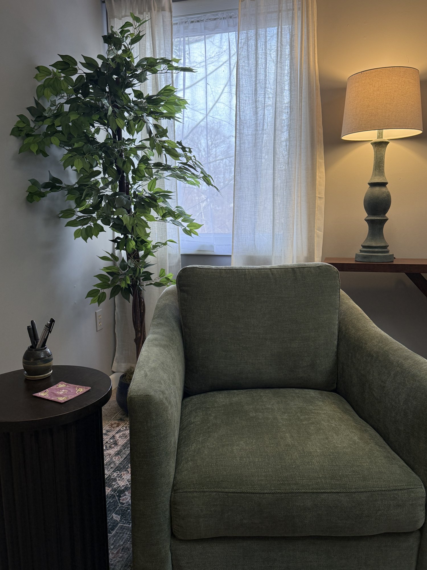 A green armchair, lamp, and window in Kristen's office