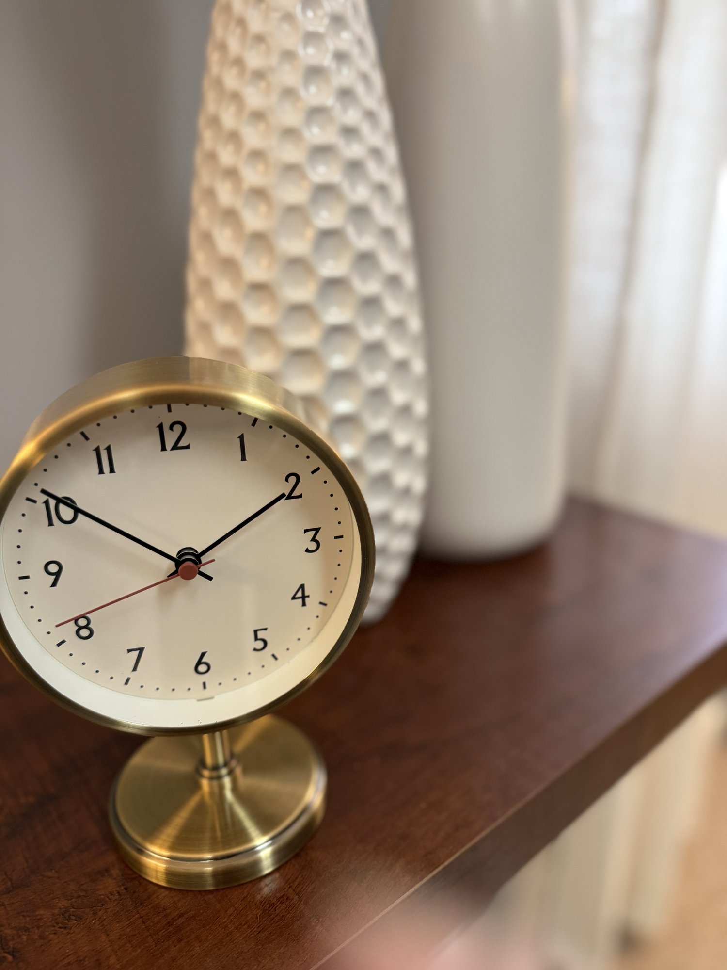 A brass desk clock on a wooden console