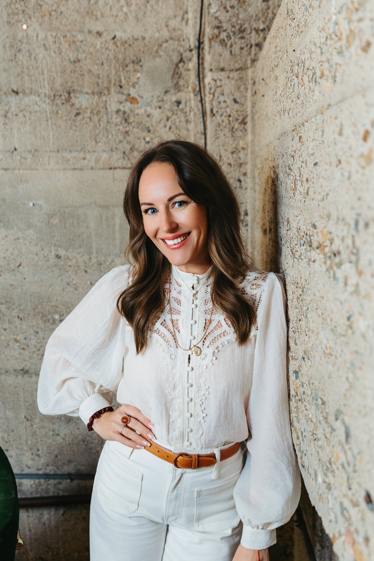 Amanda Benson standing against weathered stone, in a white outfit