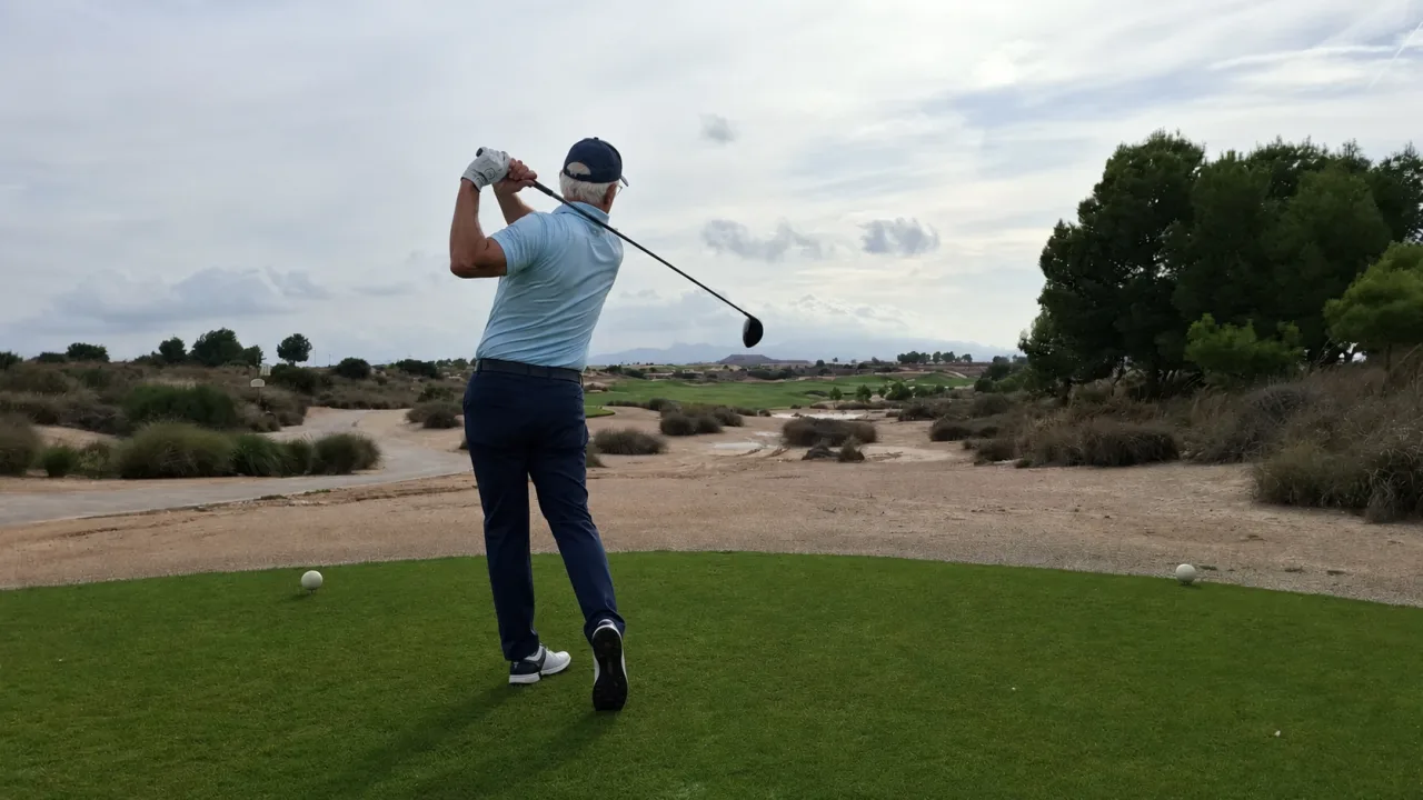 Senior golfer in balans na een drive op de golfbaan