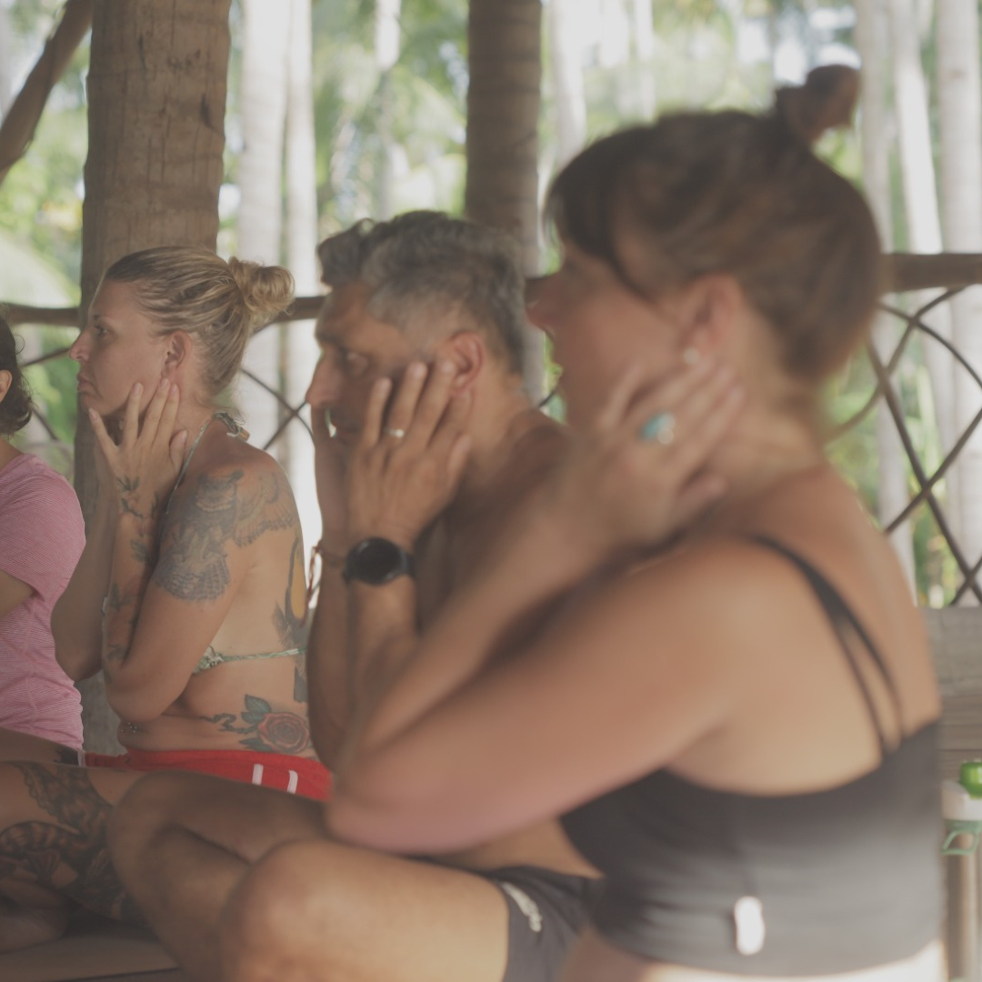 Participants in a session sitting together, hands resting on their faces, eyes turned inward