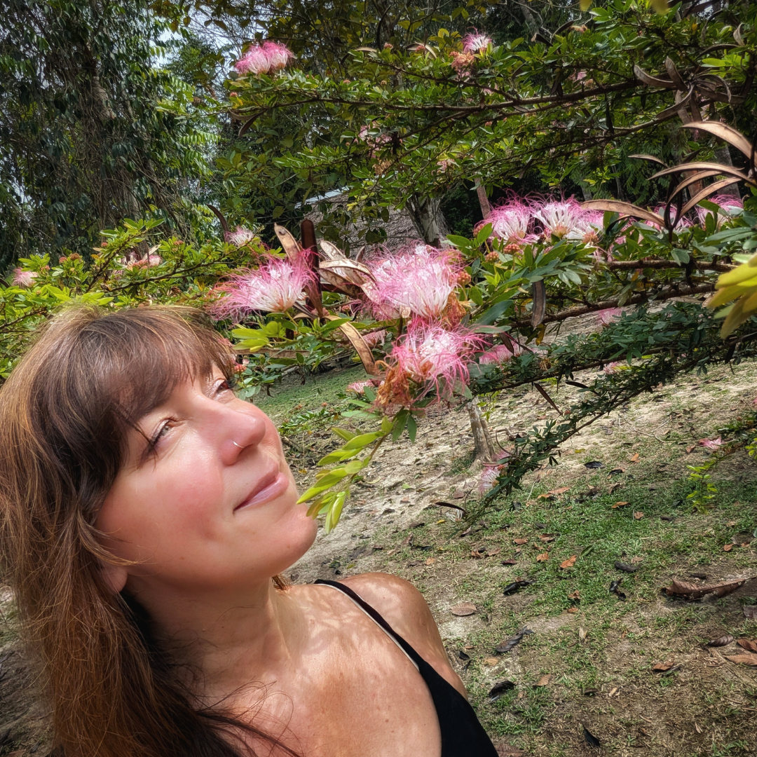 Marilyn smiling up at pink calliandra flowers in bloom