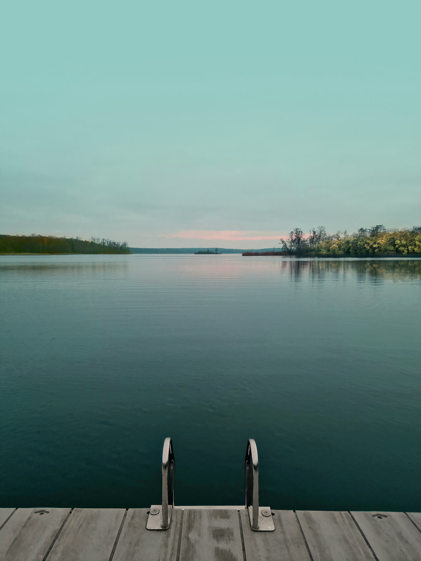 Calm lake with a wooden jetty at sunrise