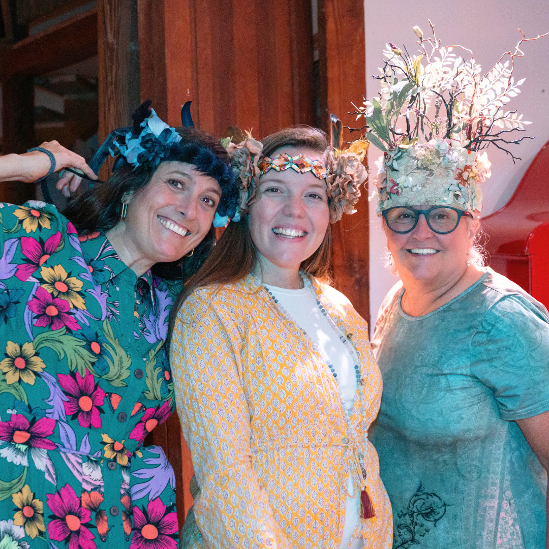 Three women in flower crowns smiling together at a gathering