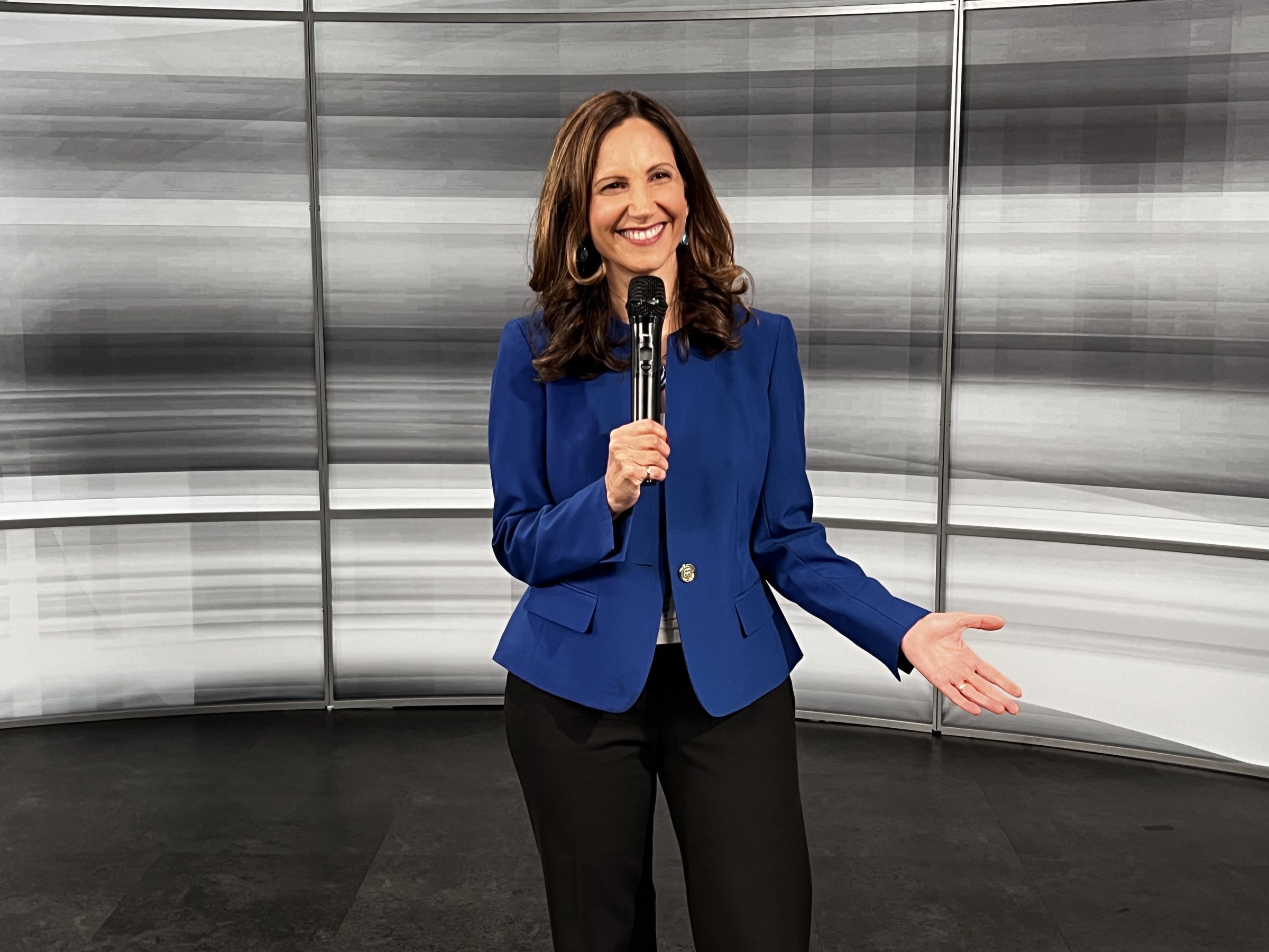 Vered Kogan speaking with a handheld microphone