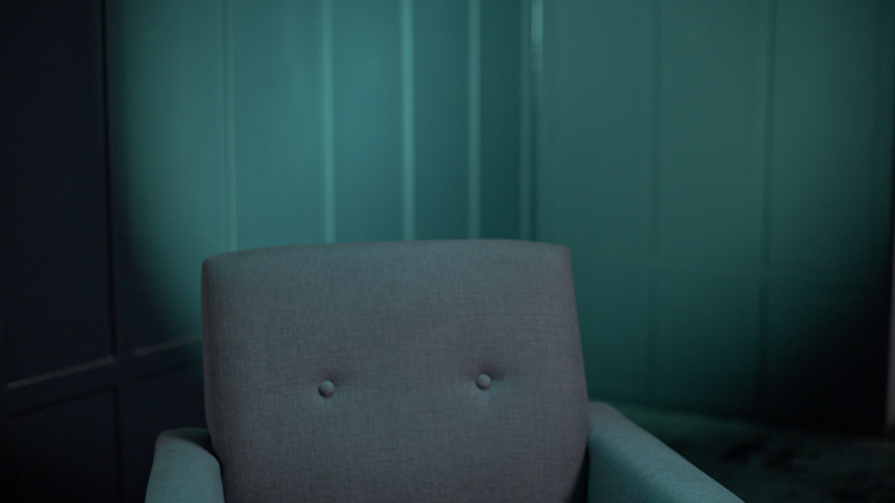Empty interview chair against a teal RGB-lit slatted studio background