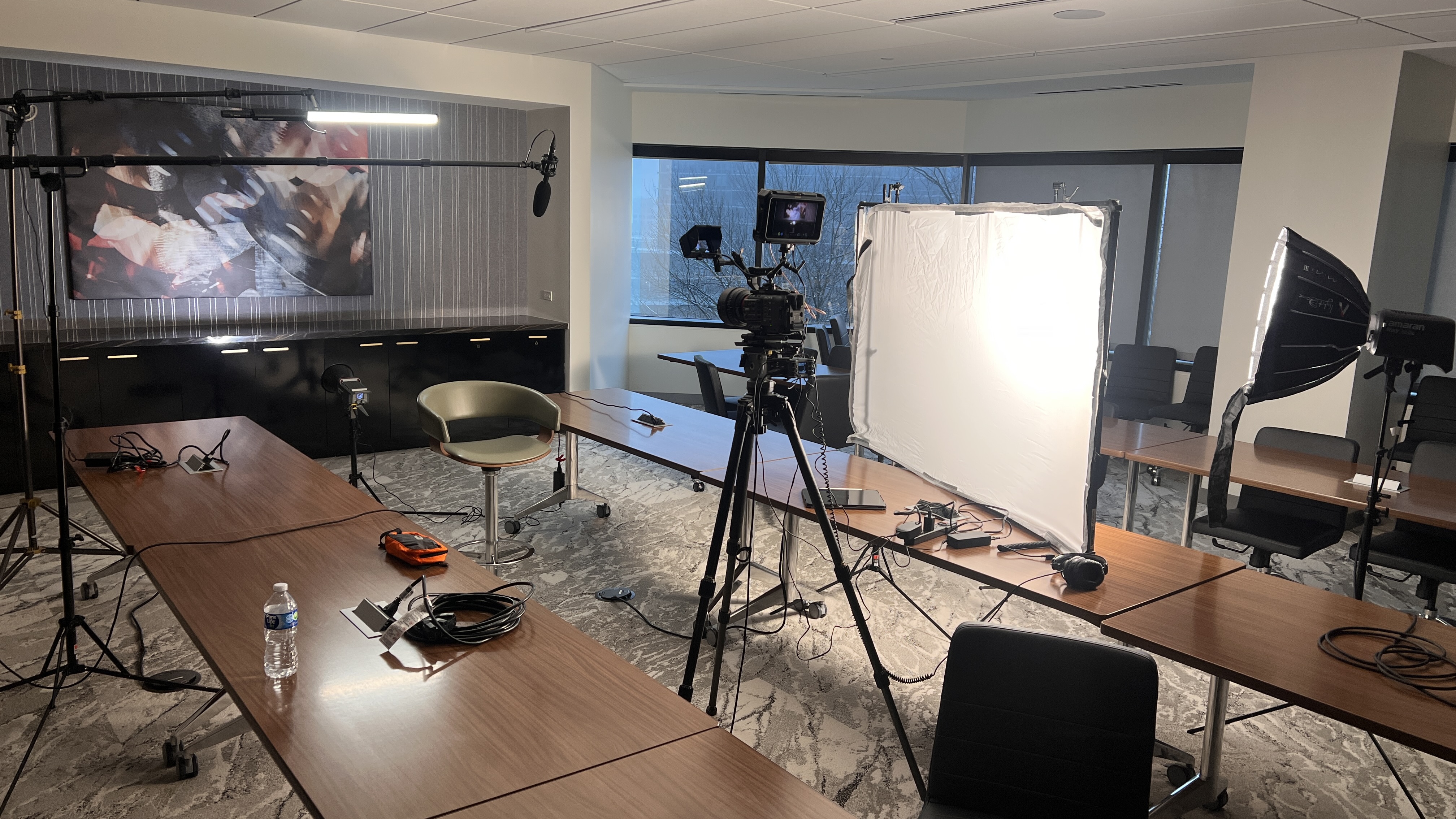 Behind-the-scenes view of the conference-room interview with camera, background light, soft key, diffusion frame, and backlight
