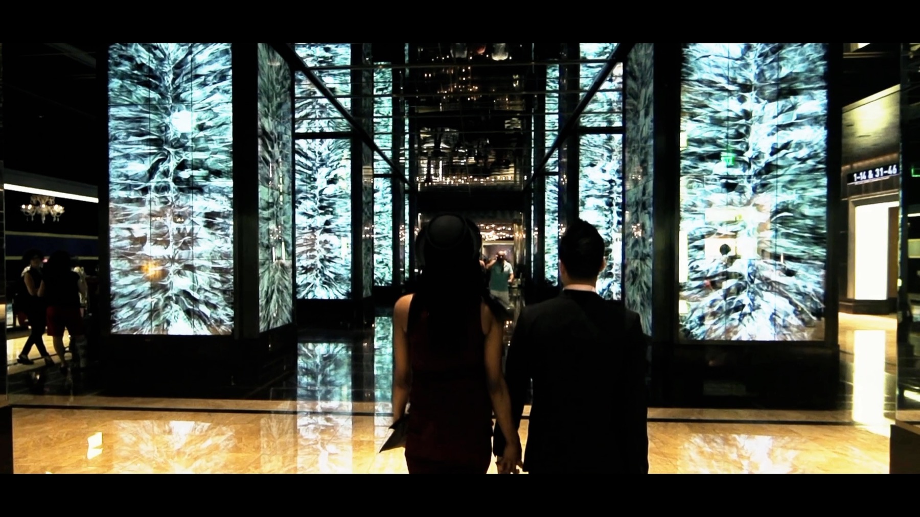 A couple entering the Cosmopolitan lobby in Las Vegas, framed against tall illuminated architectural panels