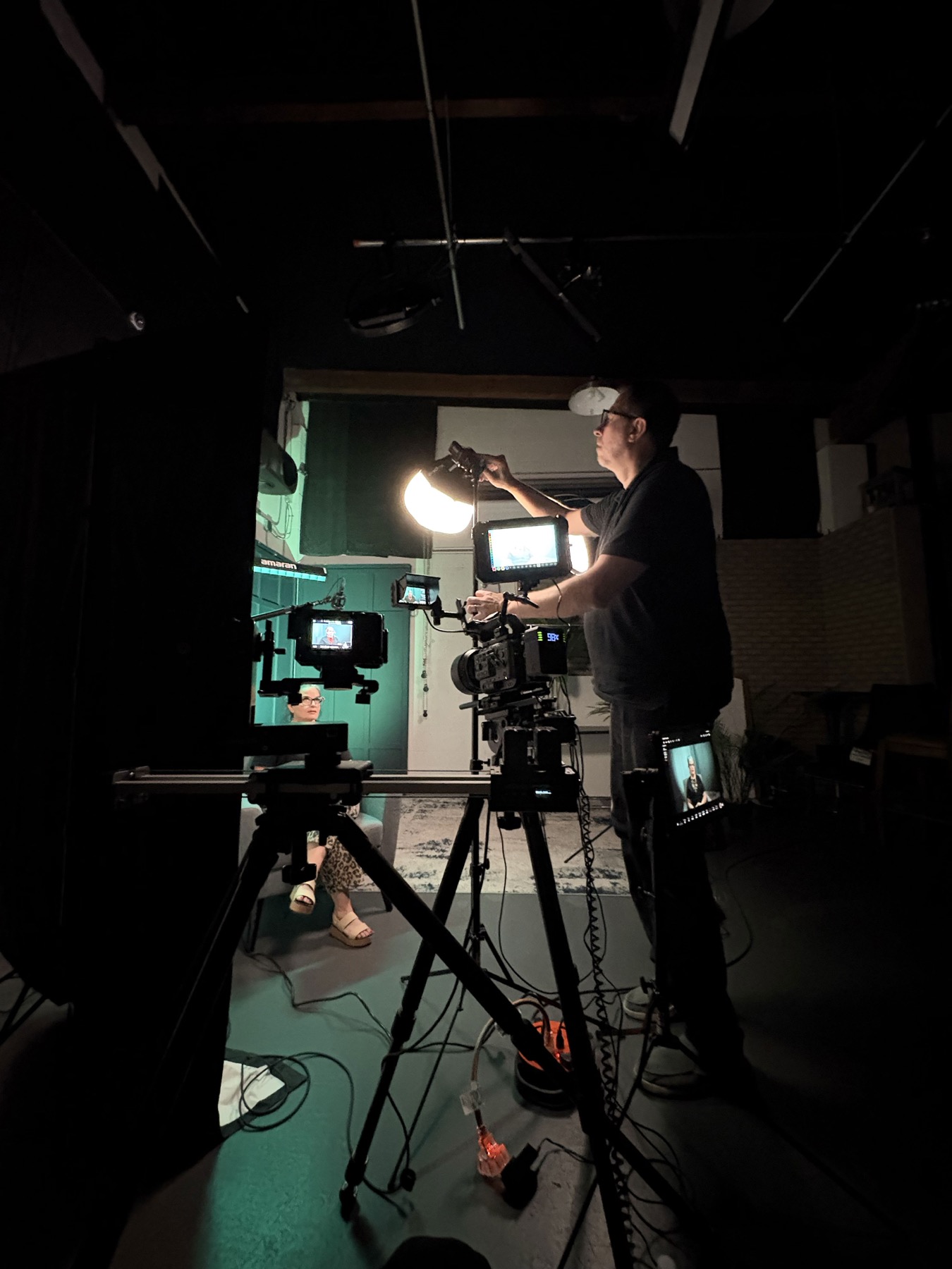 Behind-the-scenes view of Chris adding a small lantern light above the camera to reduce eyeglass-frame shadows