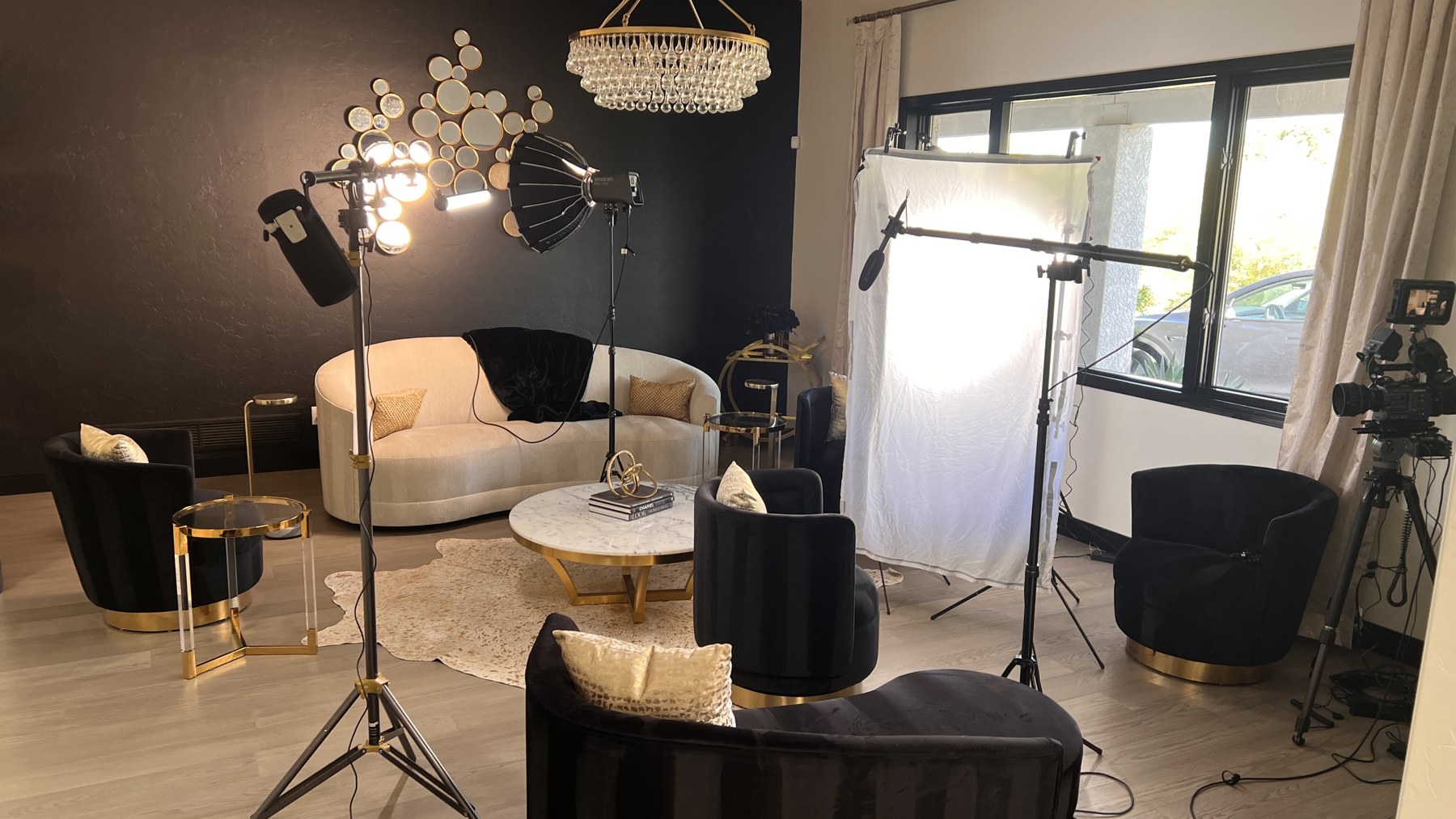 Wide behind-the-scenes view of the first living-room interview setup with diffusion, key, edge, and background lights