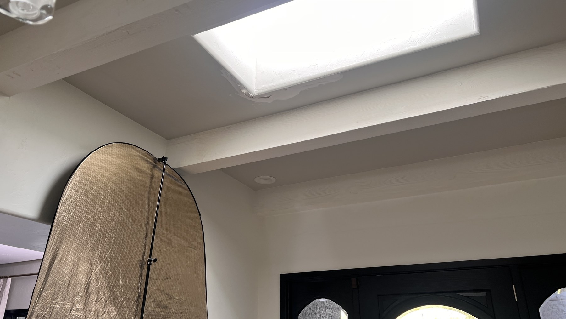 Popup negative-fill panel positioned beneath an entryway skylight to protect interview contrast