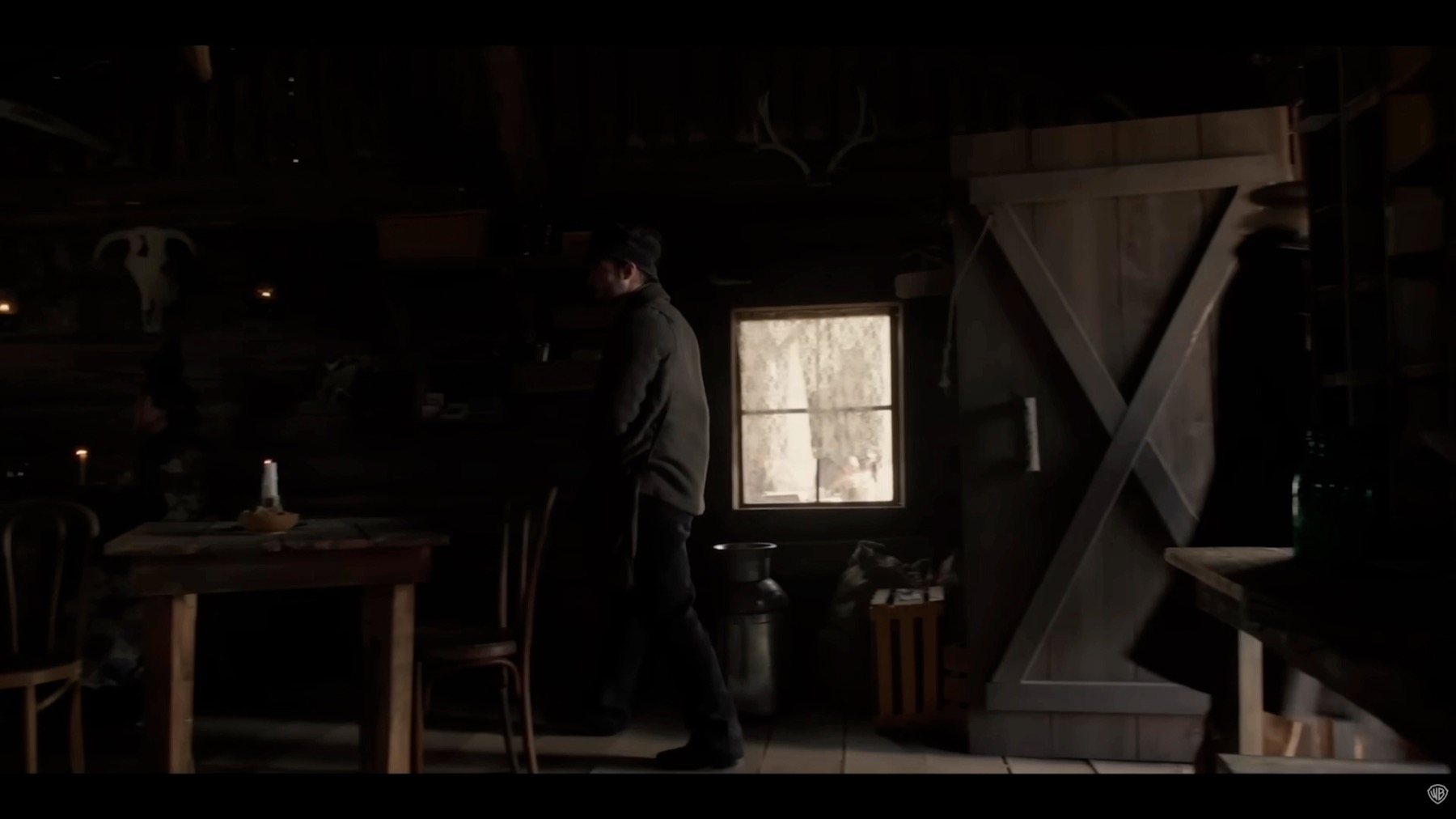 Dark outpost interior from The Unholy Trinity showing a table, bright window, open doorway, and practical architecture