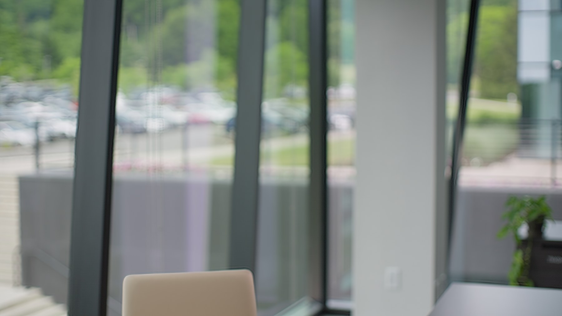 Empty interview composition looking through the glass conference room toward the exterior parking lot