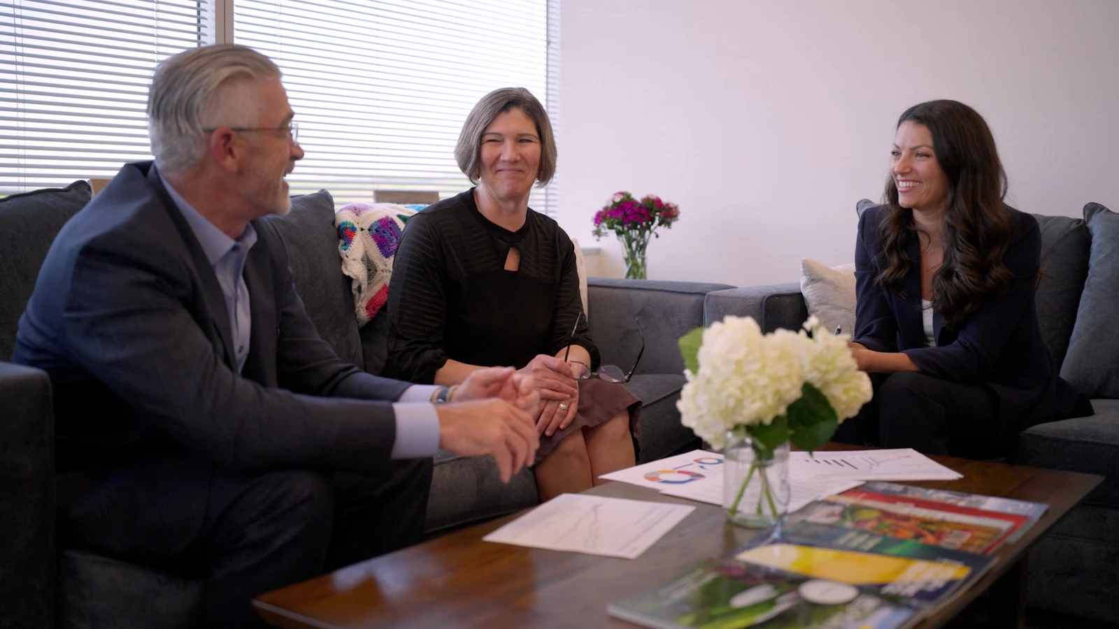 Three professionals in an office meeting framed to show their interaction and surrounding workspace