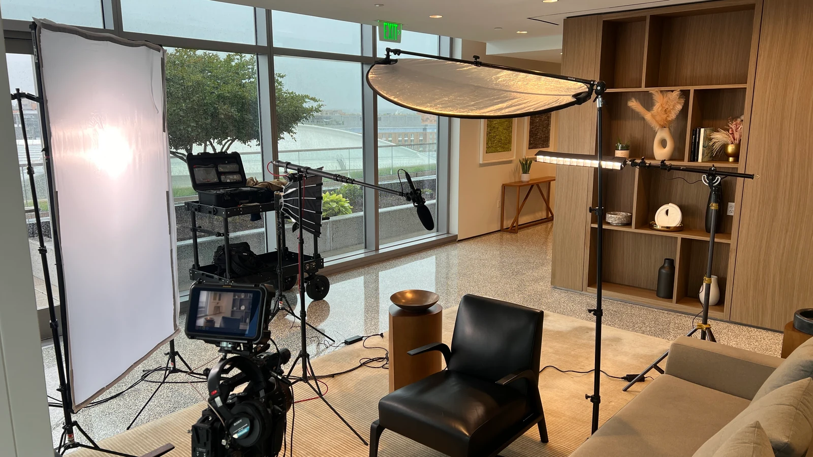Complete interview lighting setup showing camera, diffusion, overhead flag, window, and background fixtures