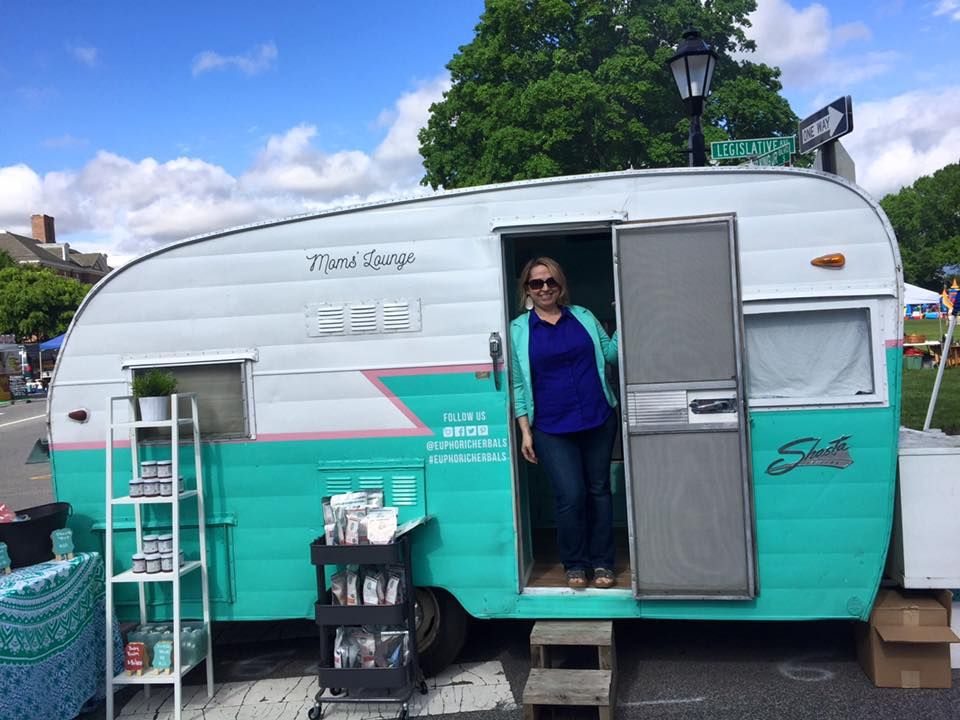 Cindy Collins standing in the doorway of her vintage camper at a local market