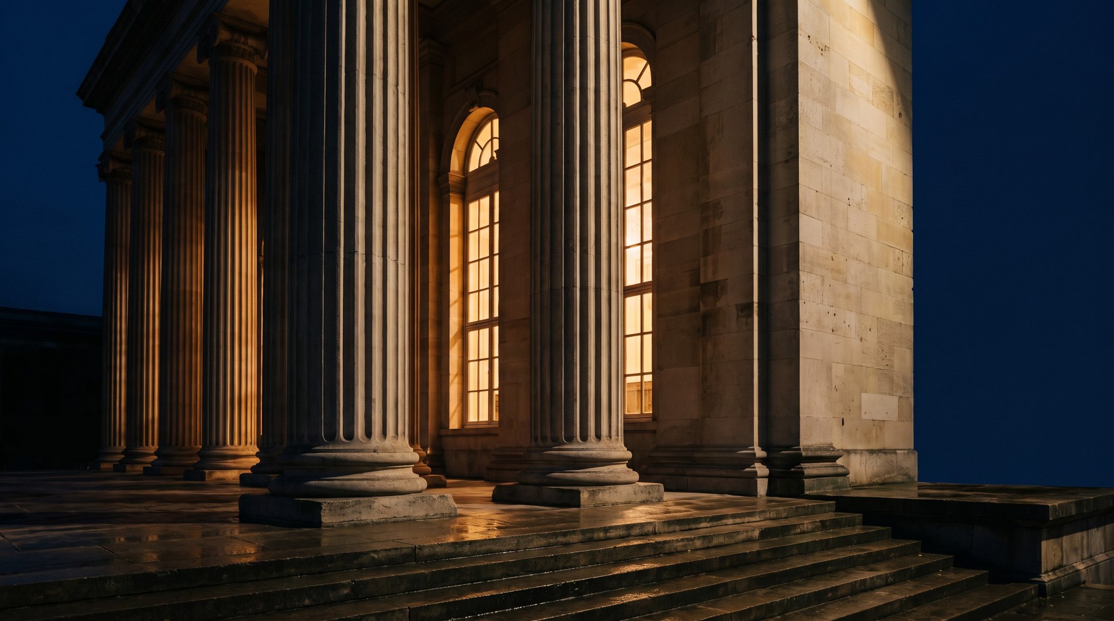 A stone colonnade at dusk, lit from within