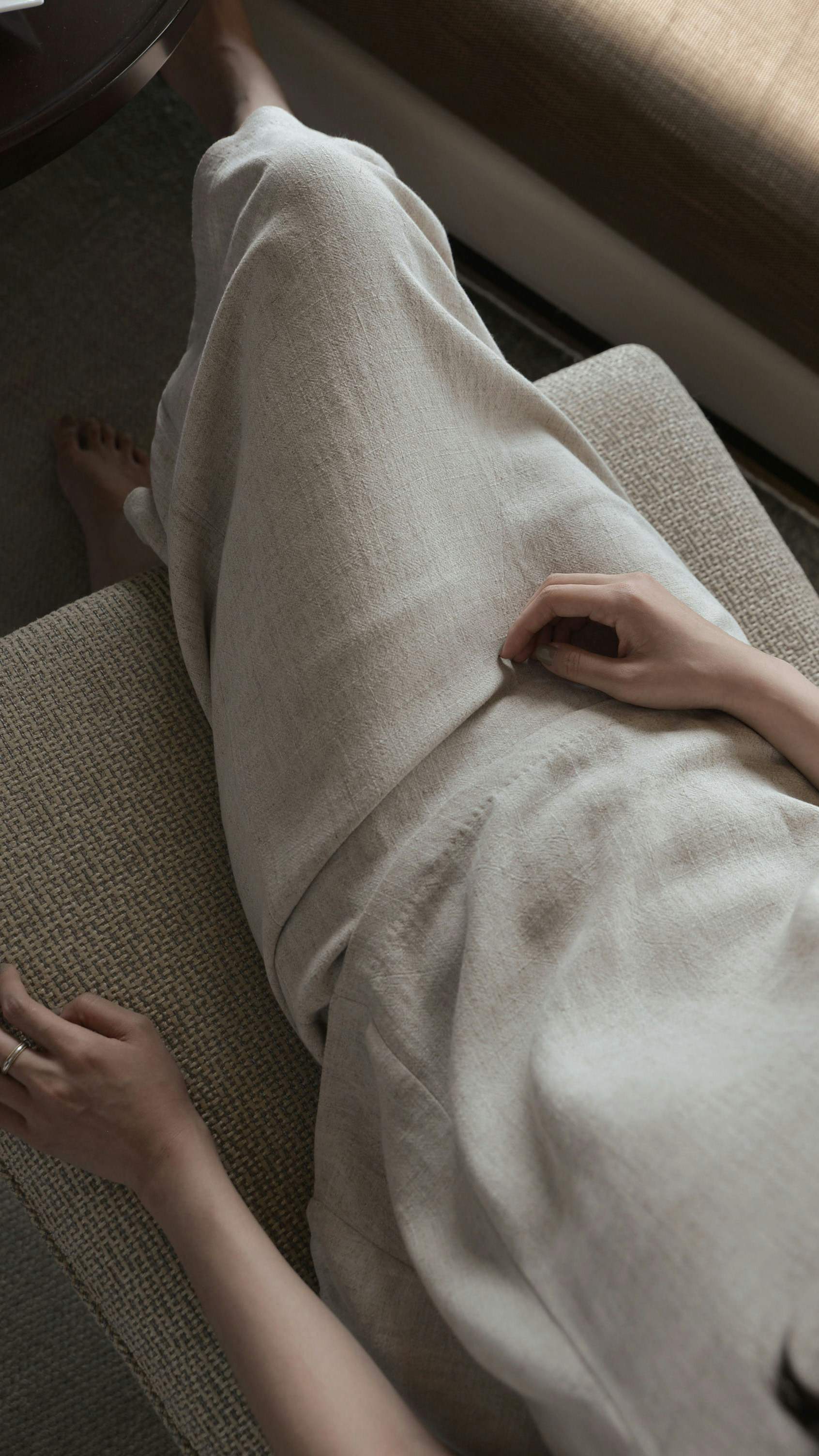 Seated in linen trousers, hands resting