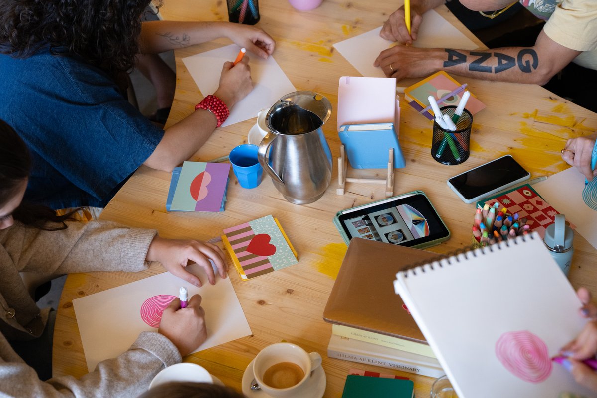 Mesa de un encuentro creativo con libretas de colores y personas dibujando