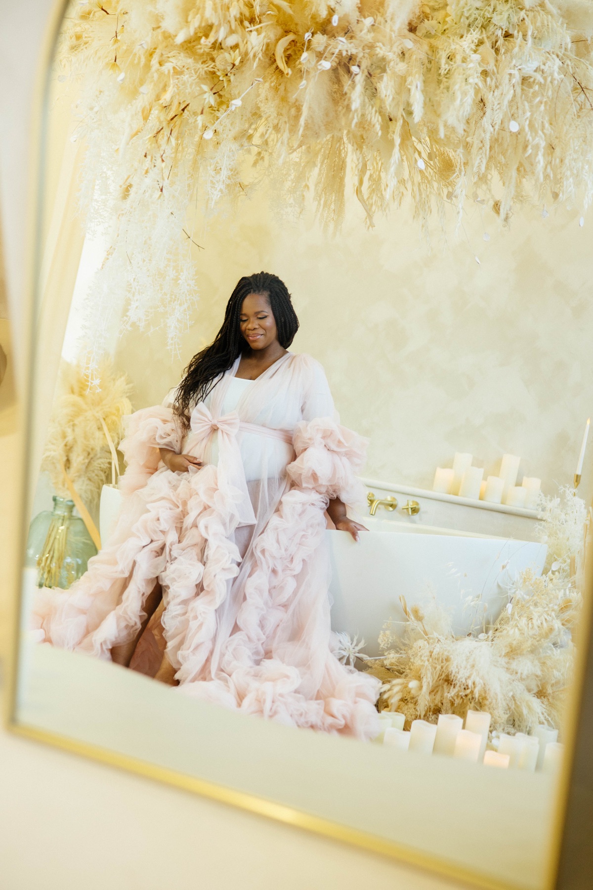 Sophie in a blush tulle robe by a bathtub, reflected in a mirror
