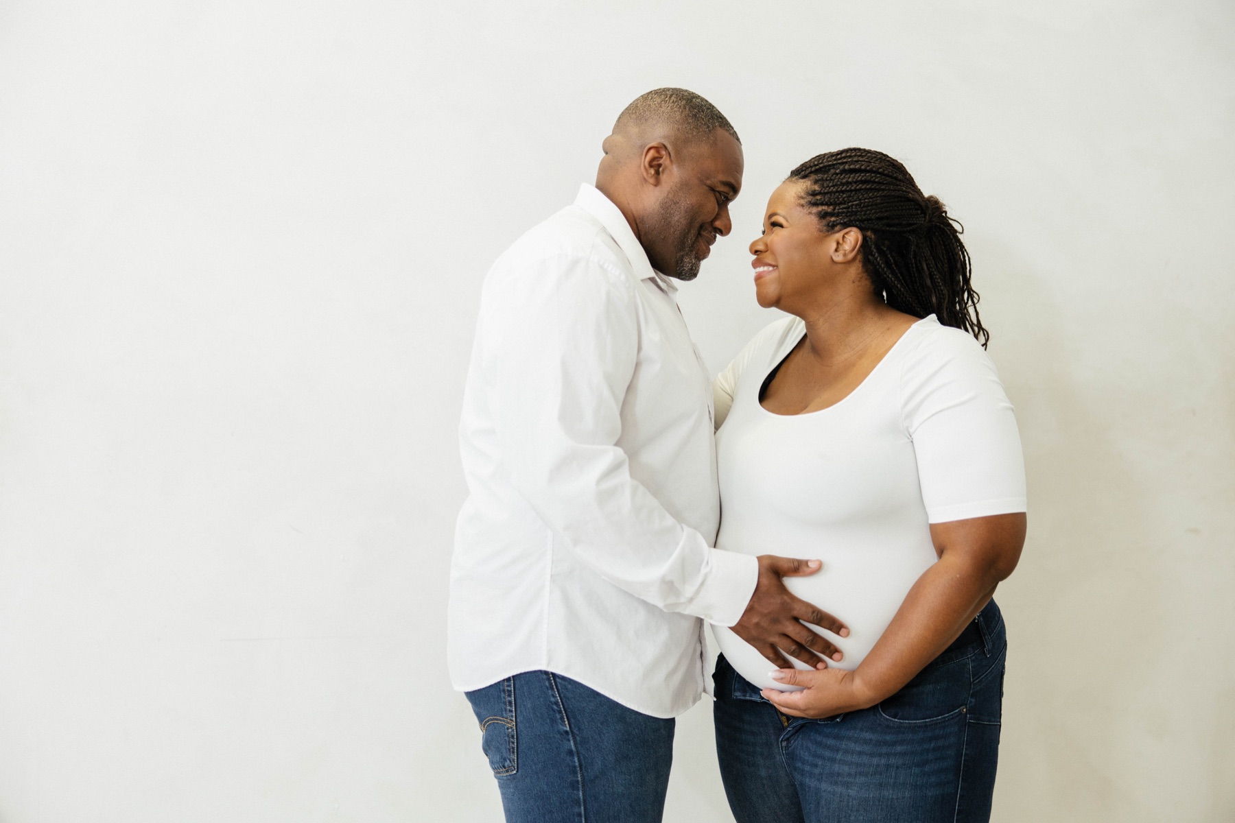 Sophie and her husband, foreheads close, hands on her belly