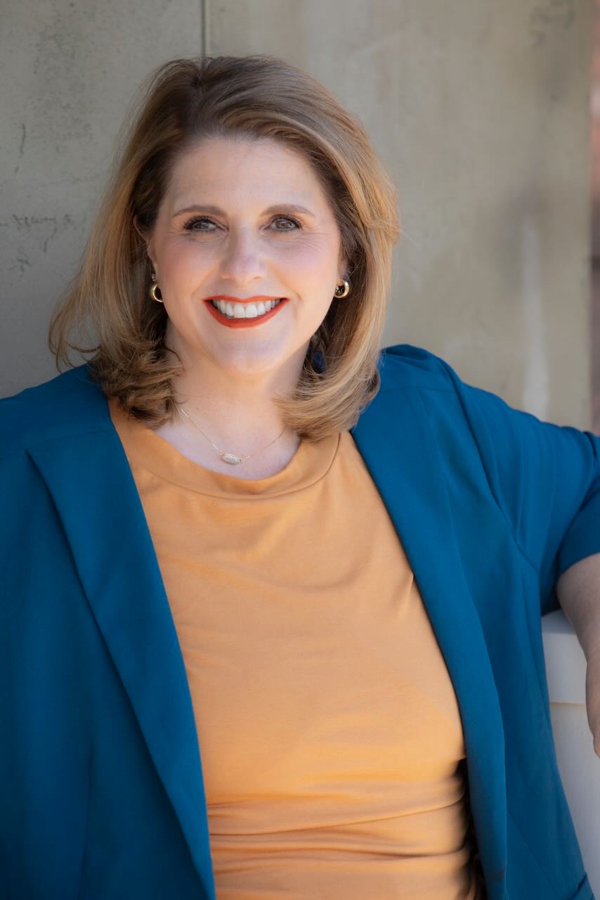 Kathy Sizemore smiling in a teal blazer and gold top