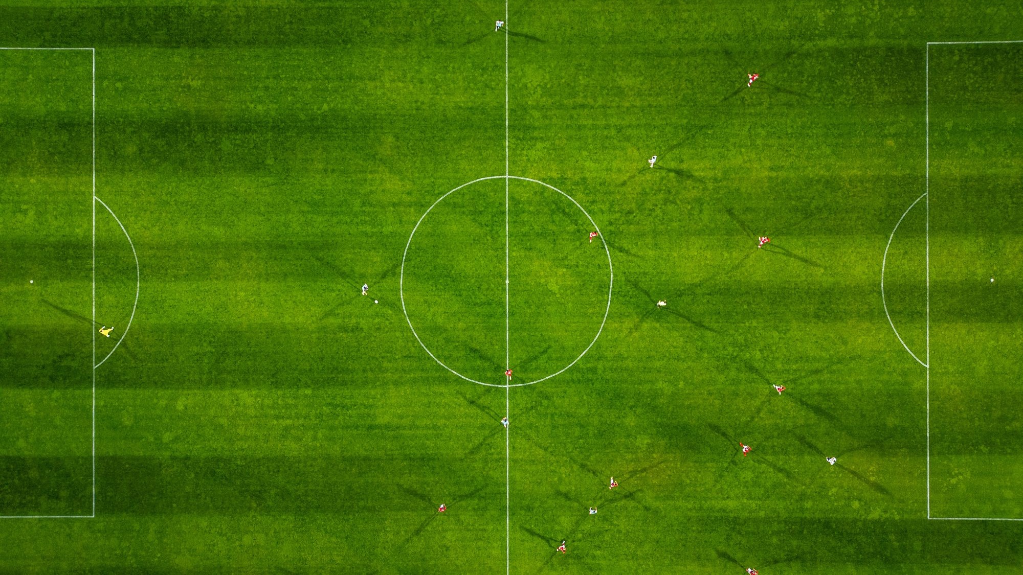 Aerial view of a football game &acirc;&euro;&rdquo; players and shadows forming relational patterns across the pitch