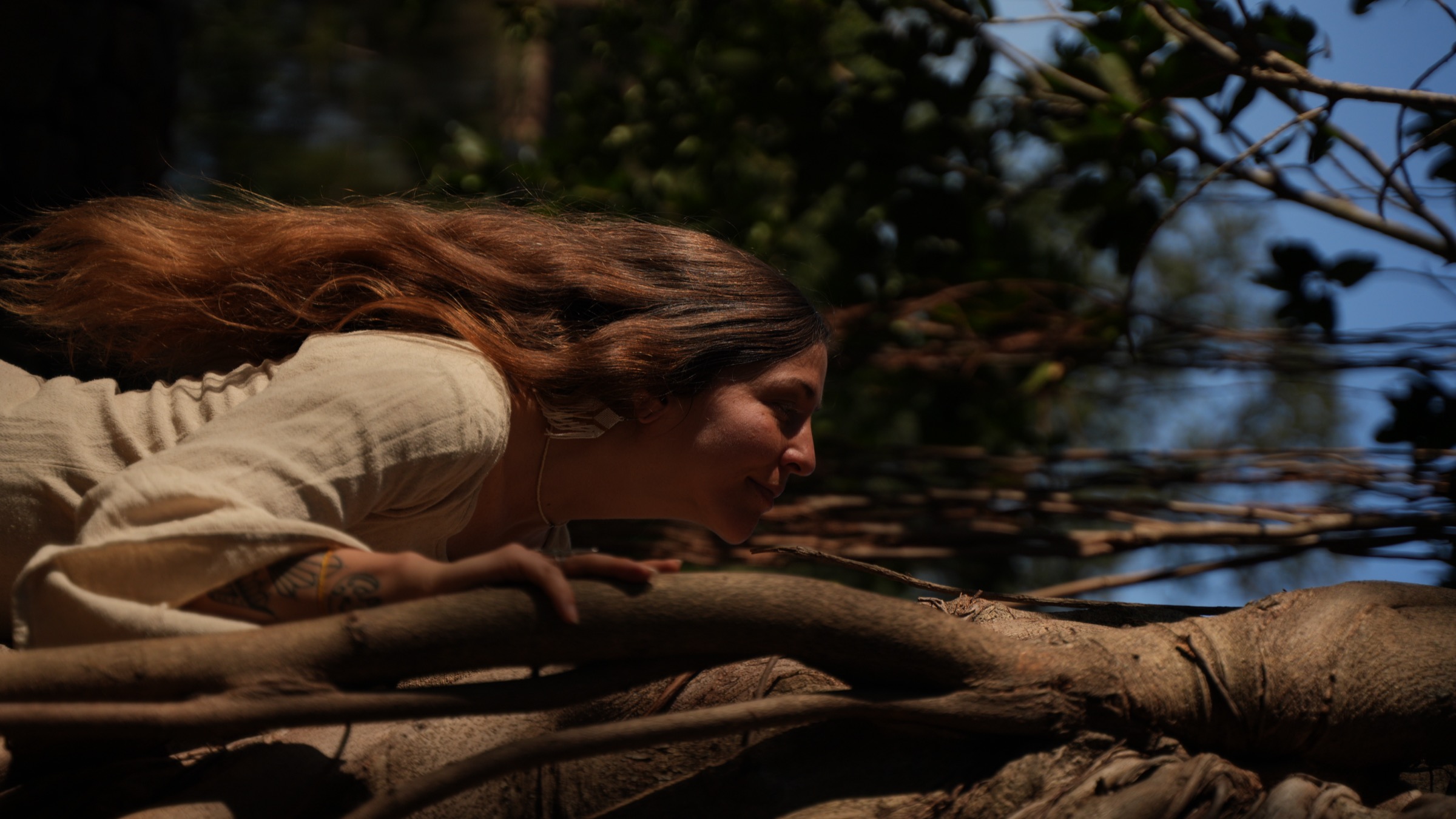 A guest resting against a banyan tree in the Sattva Campus forest at dusk