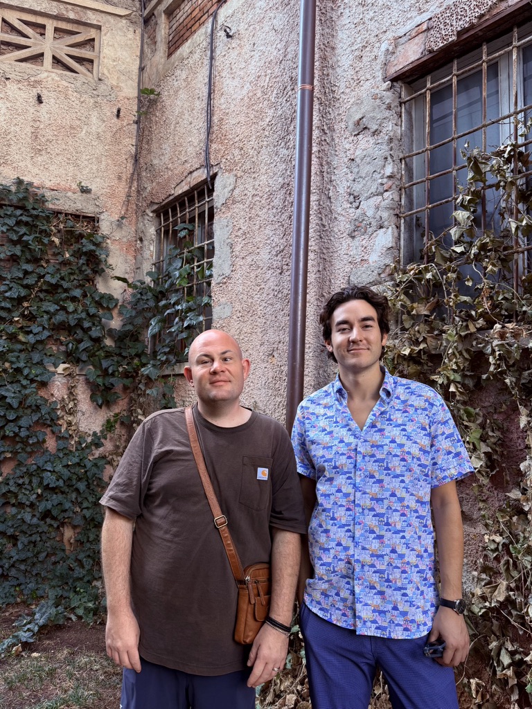 Sam on the left and Spencer on the right, beside an ivy-covered building
