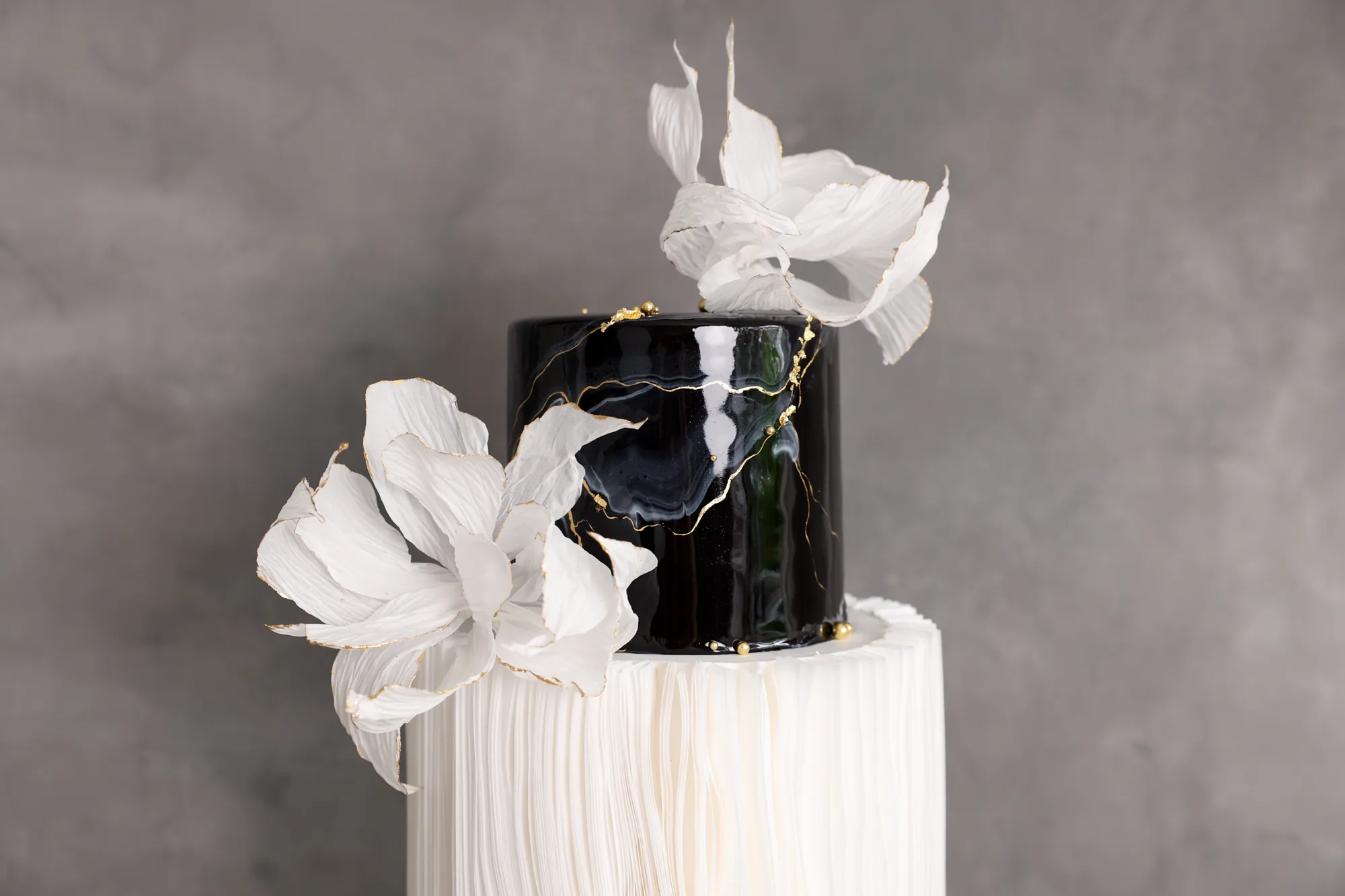 Black mirror gloss cake with gold kintsugi lines, crepe paper flowers and a wafer paper tier