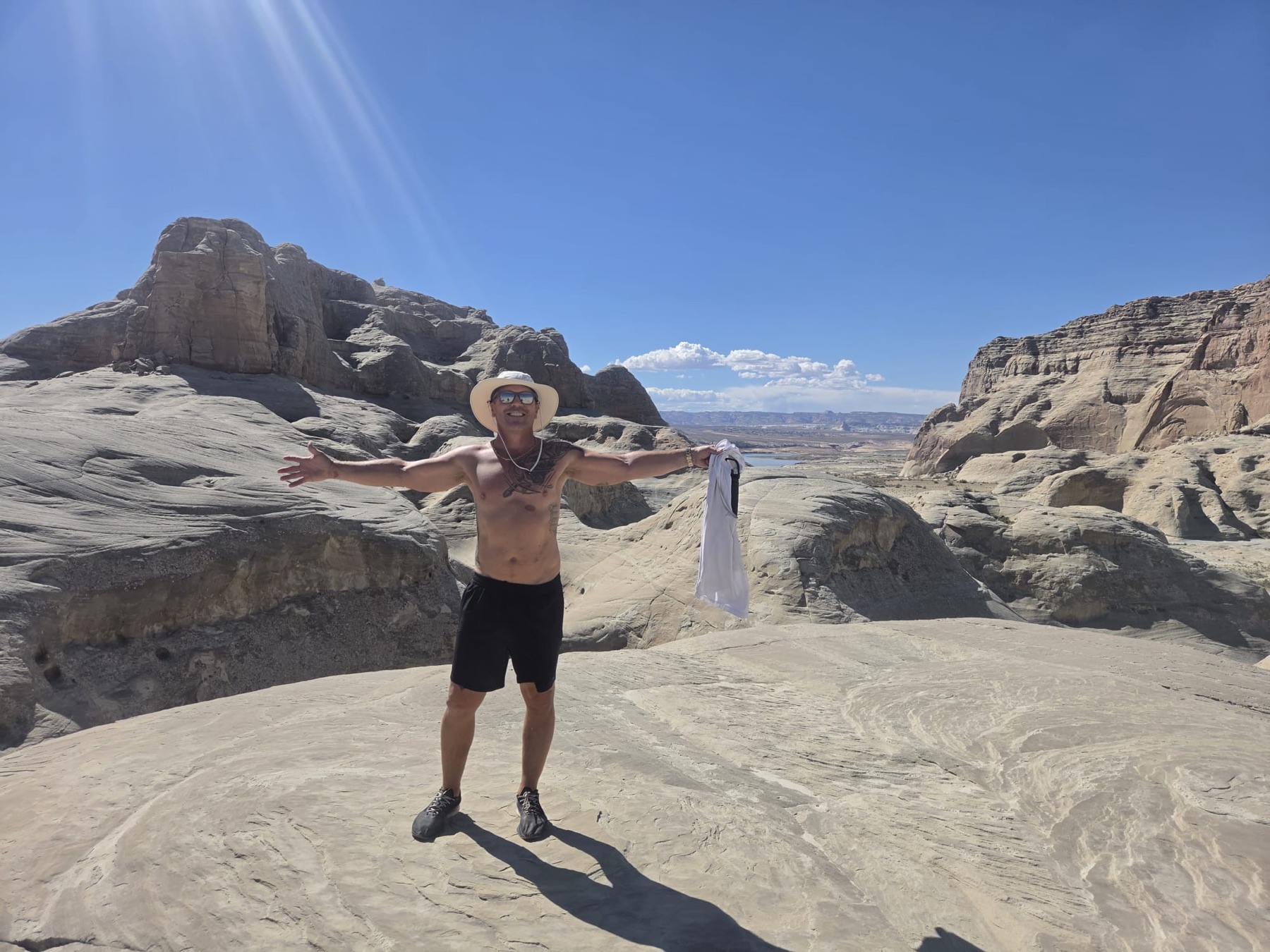 A participant standing on Lake Powell sandstone with arms outstretched