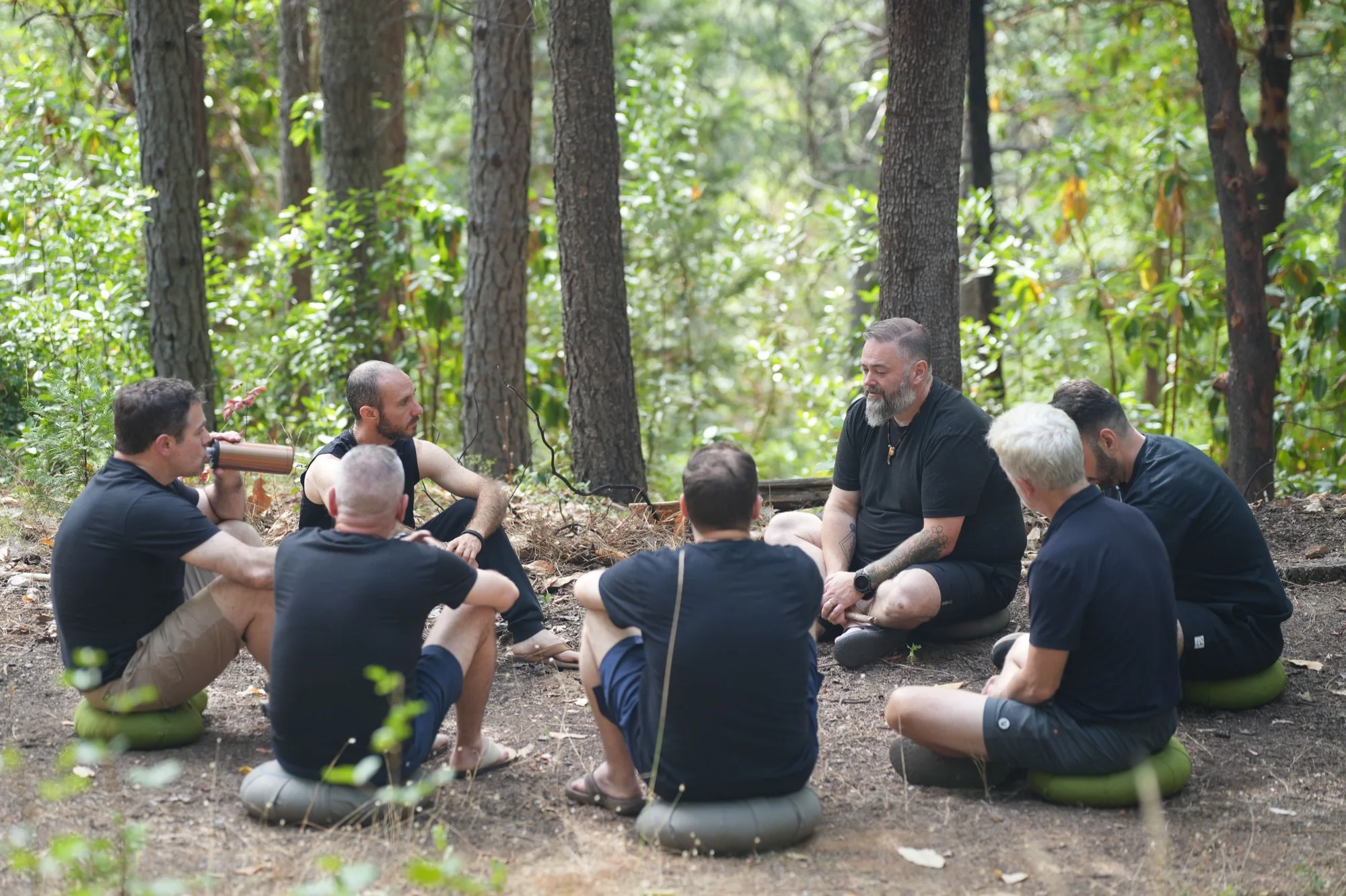 Men seated together during an Embodied Brotherhood circle in the forest