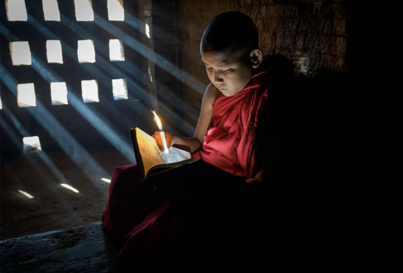 Child monk reading by candlelight