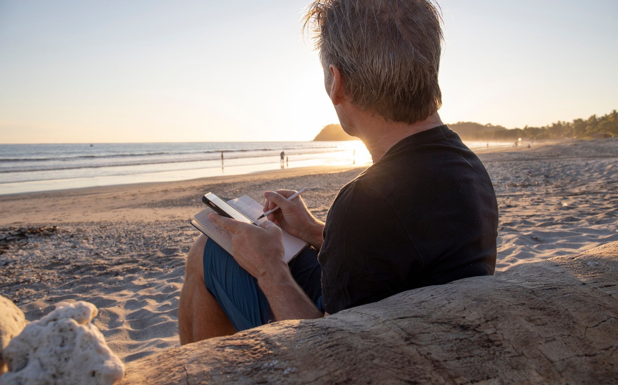 Person reflecting and writing by the beach