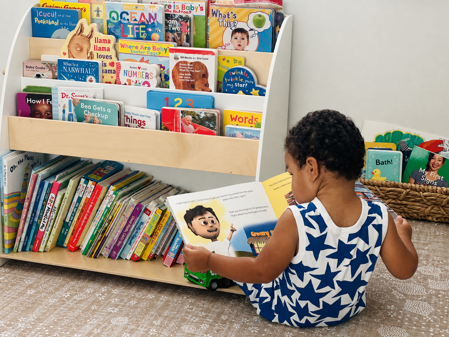 Young child reading beside a colorful display of books