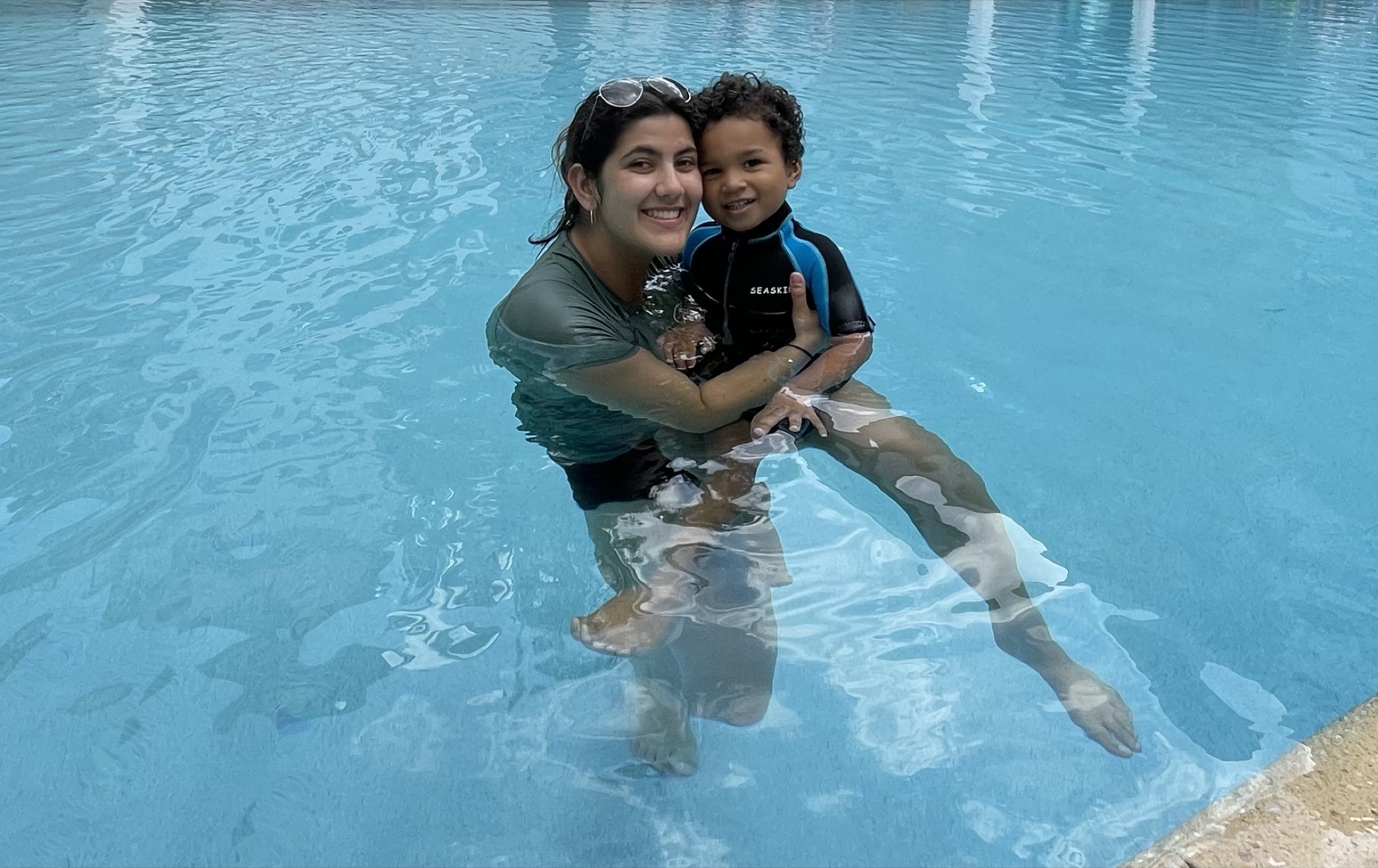 A woman and child smiling together in a swimming pool