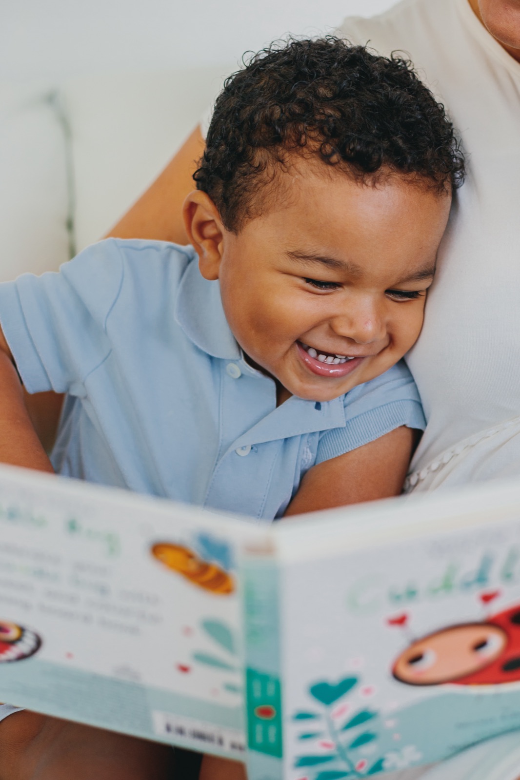 Smiling child sharing a picture book while nestled beside an adult