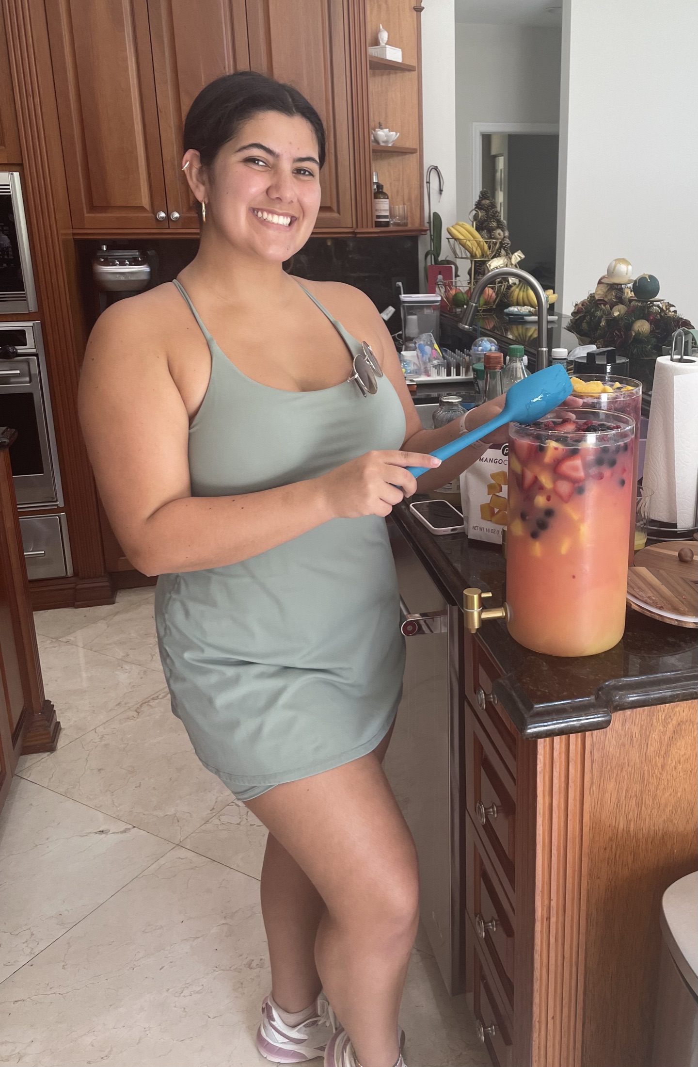 A woman in a green dress preparing fruit drinks in a kitchen