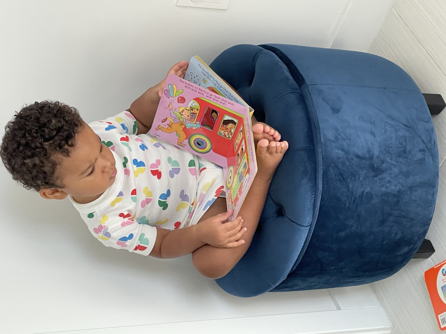 Child looking through a colorful book while seated on a blue chair