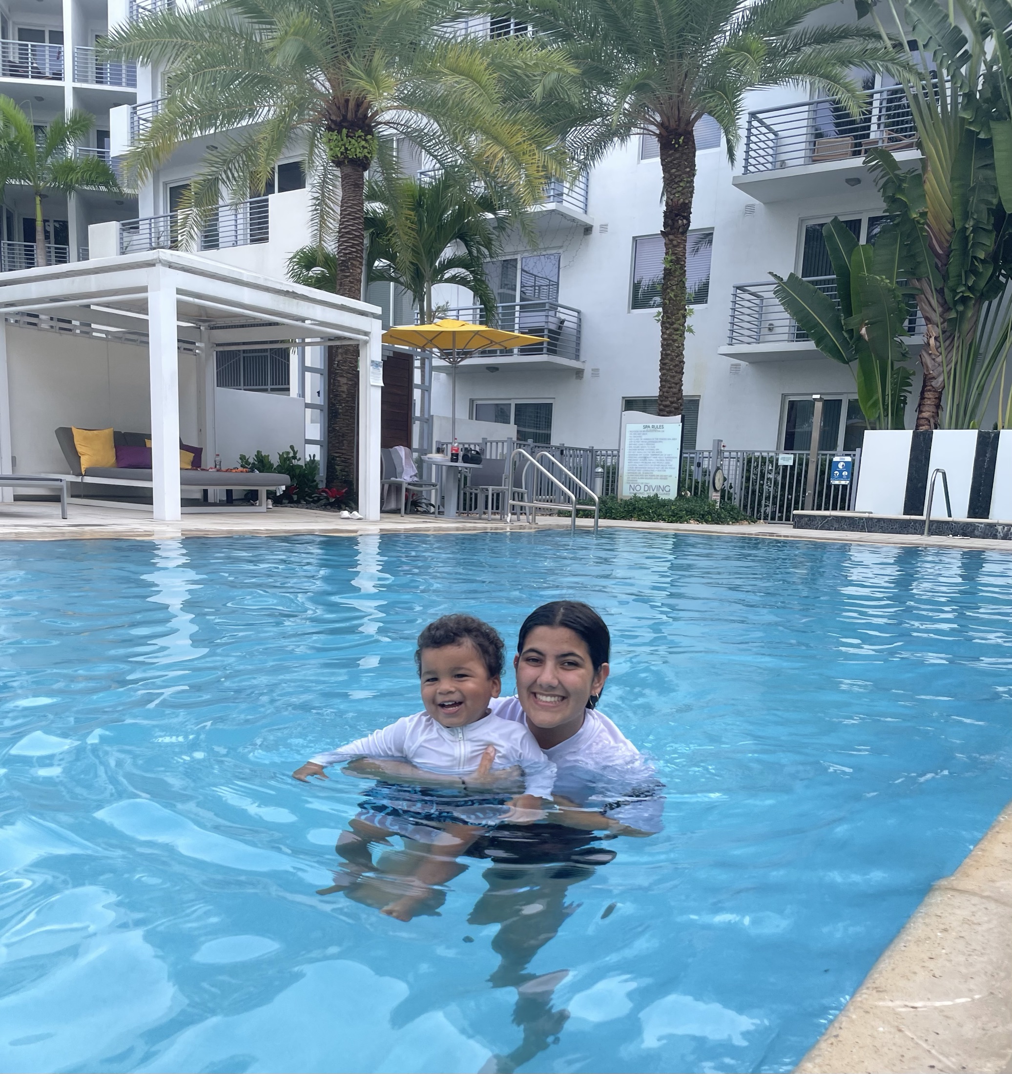 Nathalia and a boy in a white top smiling together in a swimming pool