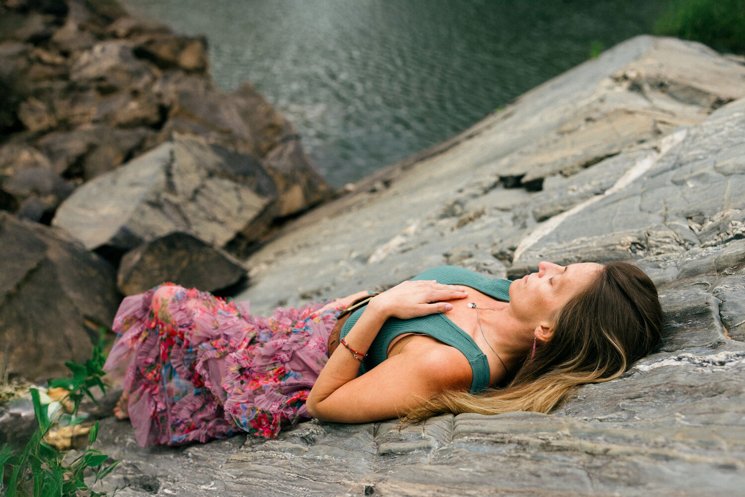 Jean-Marie lying back on the rock by the water, hand on her chest