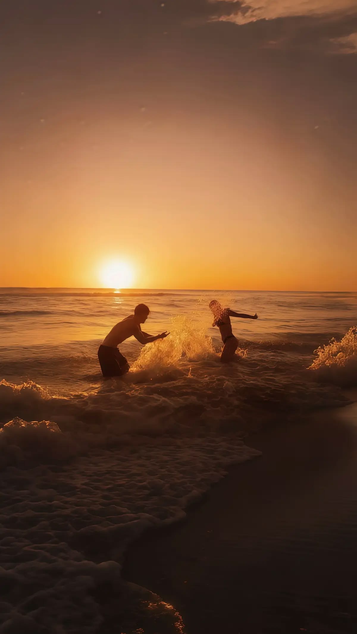 A couple playing in the surf at sunset